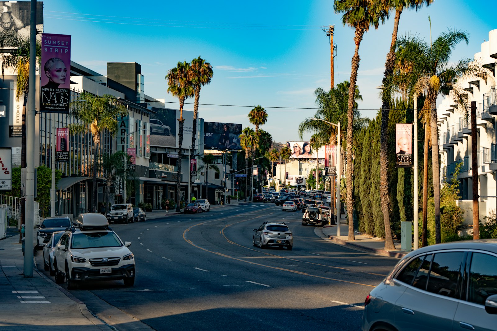 The Sunset Strip in West Hollywood on a sunny afternoon, lined with palm trees and boutique storefronts